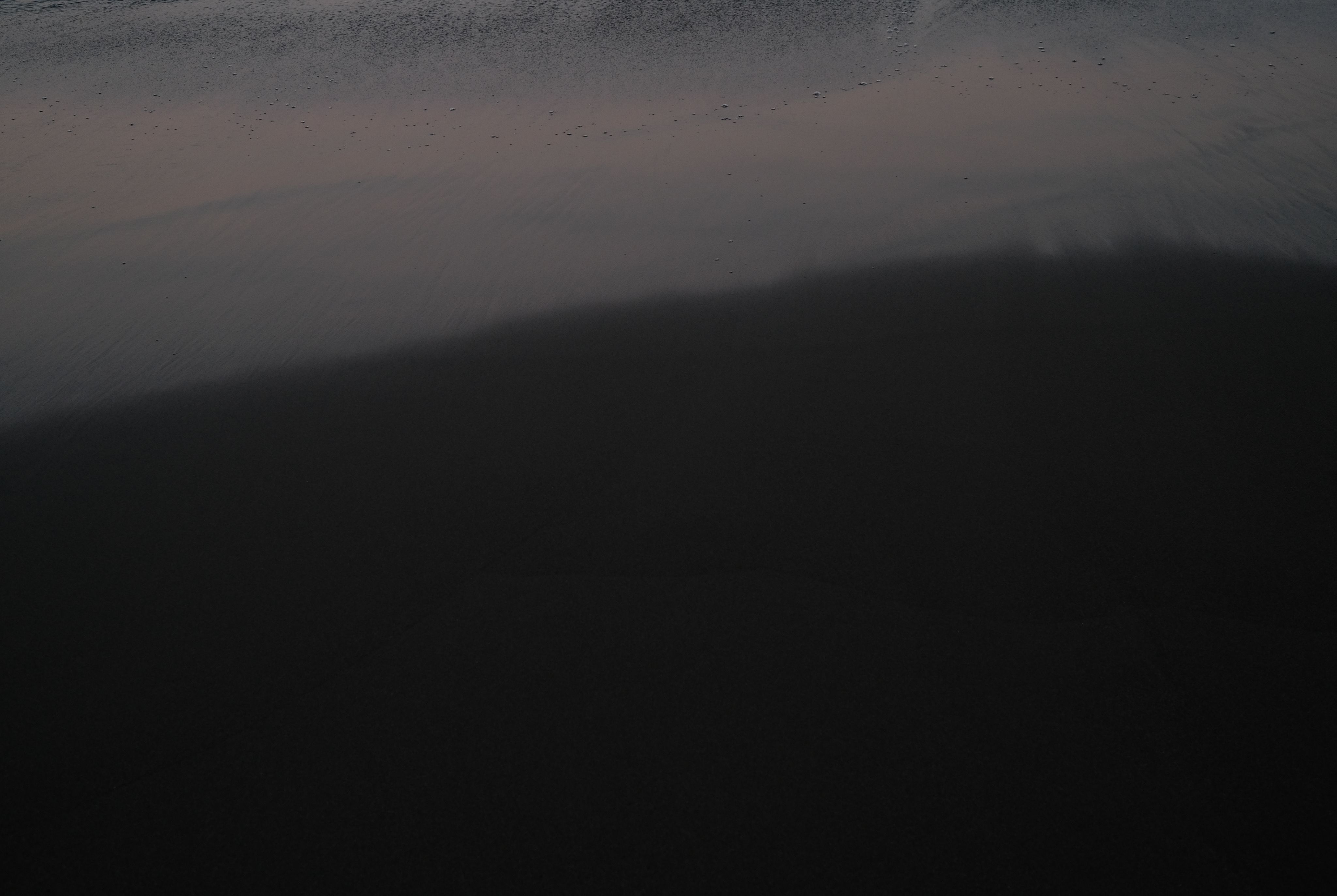 Dark shadow across a softly lit surface.